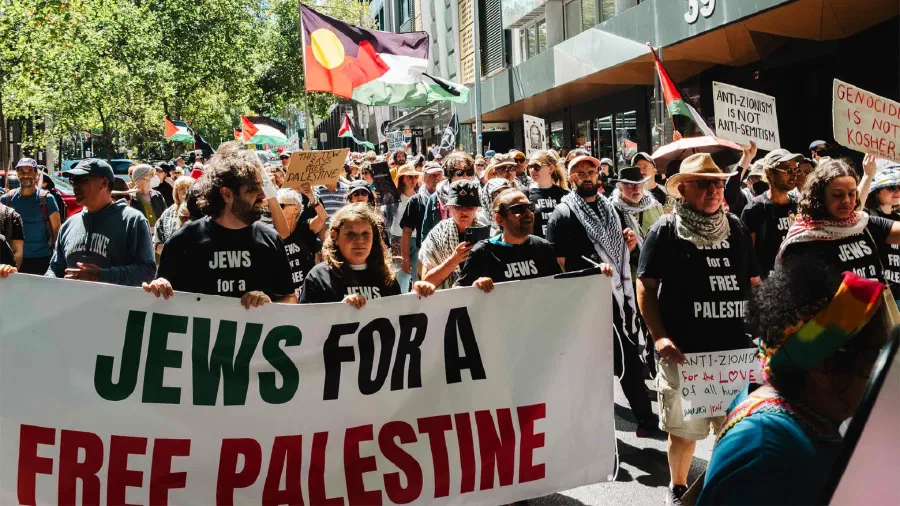 A crowd of protesters march down the street carrying pro-Palestine banners.