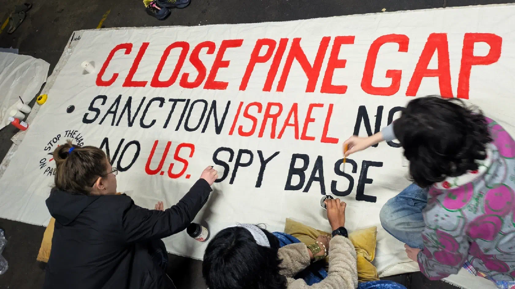 SWOP volunteers paint a banner in preparation for the Pine Gap Convergence.