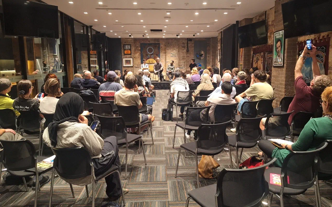 Audience members listen to speakers at a forum.