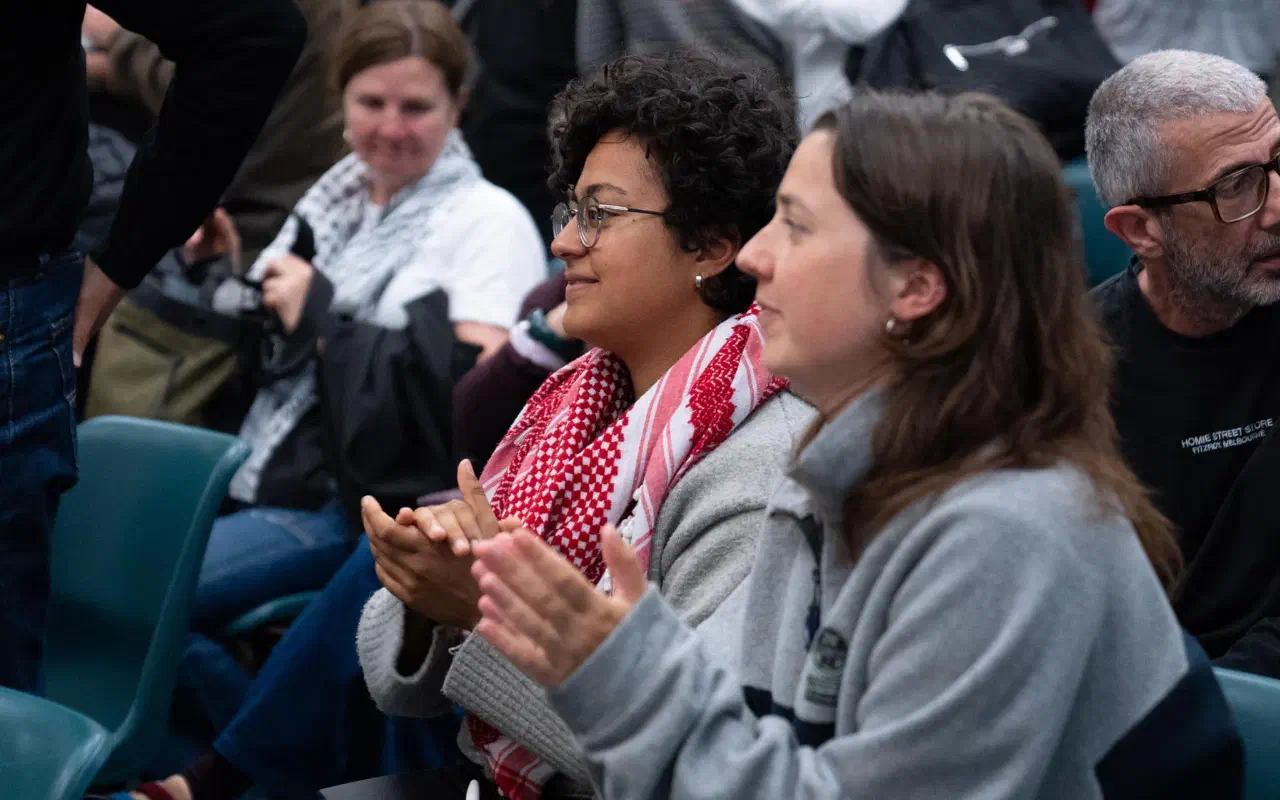 Two audience members clap at the closure of a meeting.