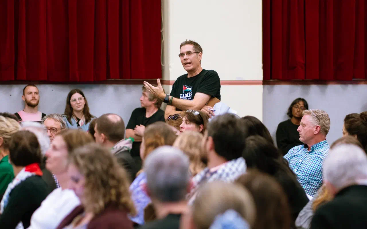 An audience member standing among the crowd asks a question.