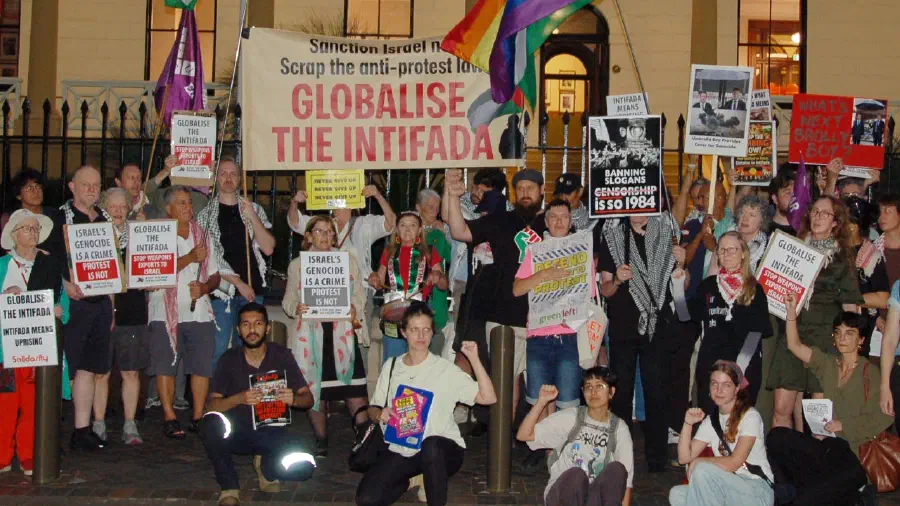 Protestors gather outside NSW Parliament House holding banners and placards.