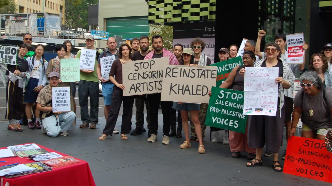 Protestors hold up signs calling on Creative Australian to reinstate artist Khaled Sabsabi.