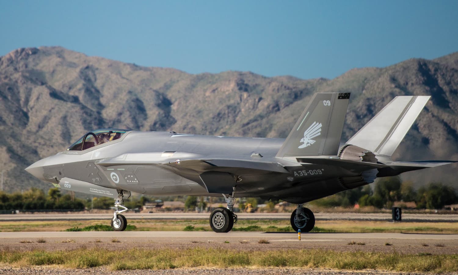 A Lockheed Martin F-35A jet sits in front of a desert landscape