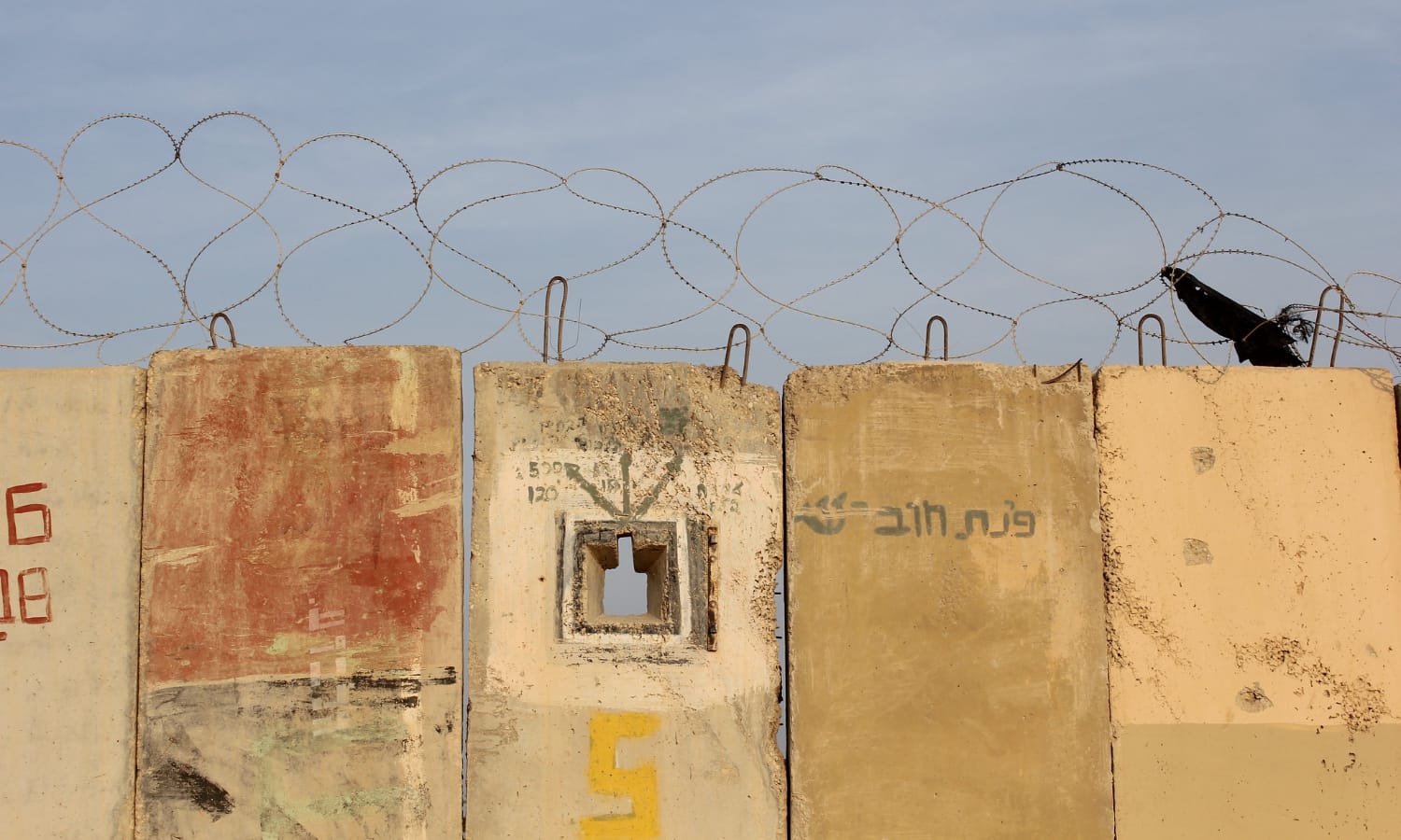 Razor wire across the top of the concrete wall 